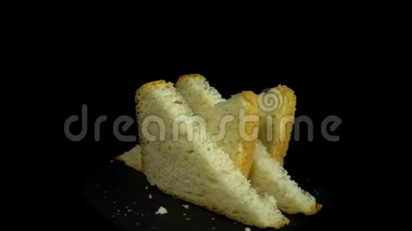 切片的白麦面包在黑色背景下旋转呈圆形运动视频的预览图