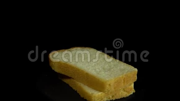 切片的白麦面包在黑色背景下旋转呈圆形运动视频的预览图