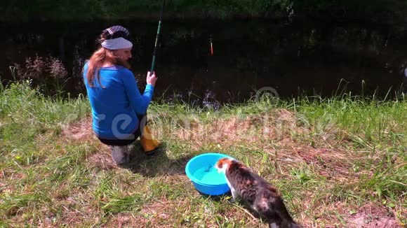 女人在湖岸钓鱼用桶水钓鱼视频的预览图