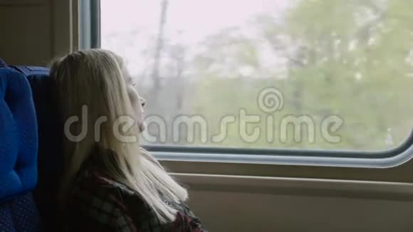 年轻的白种人女人坐火车旅行时透过窗户看视频的预览图