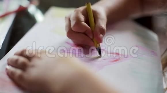 小女孩坐在桌子旁用蜡笔画画近点视频的预览图