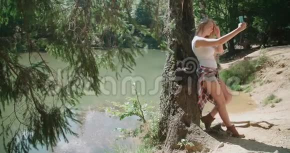 美丽的白种人女孩在阳光明媚的日子里在湖边度过时光视频的预览图