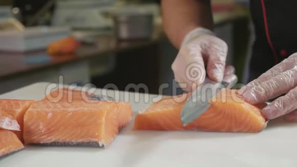 在寿司吧里在手套里为寿司厨师切鲜鲑鱼视频的预览图