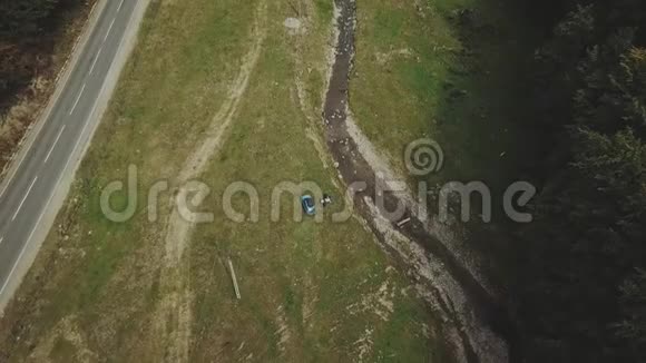 空中观车骑在路上的针叶林中的群山游客在汽车附近自拍视频的预览图