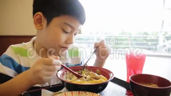 快乐的亚洲男孩吃日本午餐看着相机视频的预览图