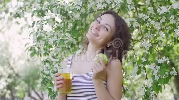 一个女人在苹果的背景下从罐子里倒果汁视频的预览图