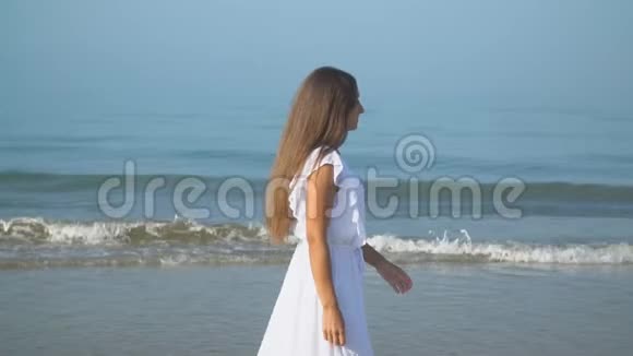 穿着白色裙子的女孩走在海边视频的预览图