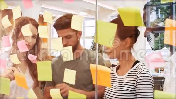 男性和女性的企业高管在阅读粘性笔记时讨论数字平板电脑视频的预览图