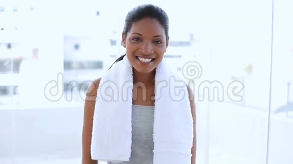 一位美丽的女人拿着毛巾在她的瓶子里喝水视频的预览图
