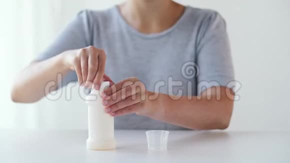 女人把糖浆从瓶子里倒入药杯视频的预览图