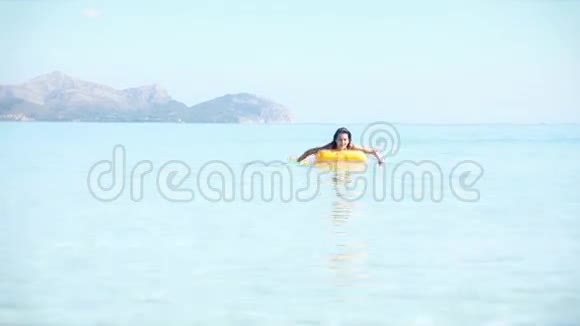 年轻女子坐在黄色的游泳池筏子上视频的预览图