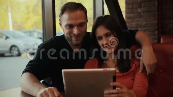 年轻夫妇使用数字平板电脑咖啡馆视频的预览图