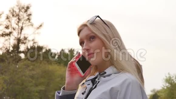 公园里漂亮的年轻女人用电话傍晚漫步市中心一个年轻的女人走在视频的预览图