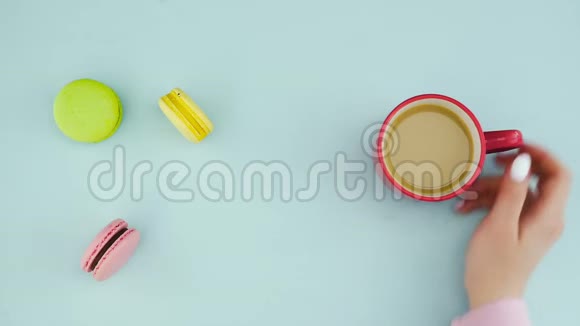 马卡龙或马卡龙在糊状蓝色表面与咖啡在红色杯视频的预览图