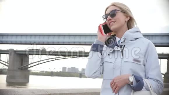 公园里漂亮的年轻女人用电话傍晚漫步市中心一个年轻的女人走在视频的预览图