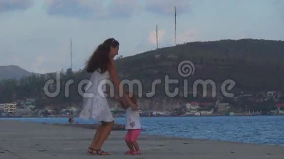 一个美丽的女孩和婴儿在海边跳舞视频的预览图