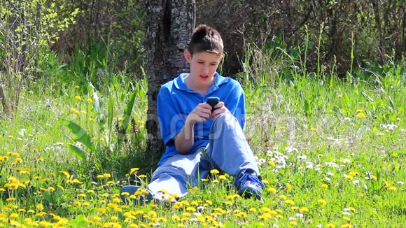 带手机的男孩坐在户外用手机的男孩视频的预览图