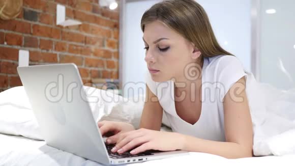 头痛疲惫的女人在床上工作视频的预览图