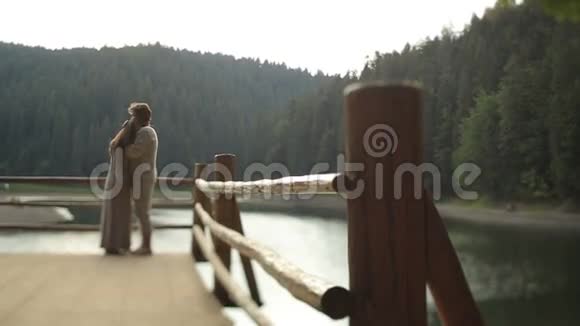 美丽的夫妻相爱穿着传统的乌克兰服装轻轻地拥抱在山湖码头上呼吸视频的预览图