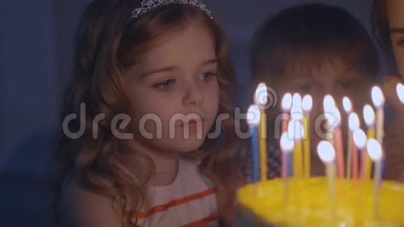 一个小女孩看着节日蛋糕上的蜡烛慢慢地许愿视频的预览图