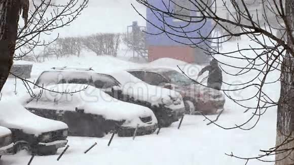 城市里下着大雪停车场里白雪覆盖的汽车视频的预览图