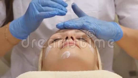美容师在病人的皮肤上涂霜视频的预览图