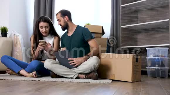 漂亮的年轻夫妇坐在他们新公寓的地板上视频的预览图