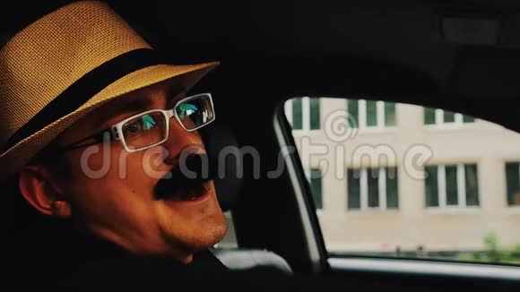 戴着胡子戴着帽子的人戴着眼镜坐在车里唱歌夏日乐趣视频的预览图
