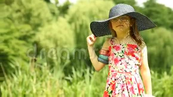小女孩小孩在草地上摘下草帽视频的预览图