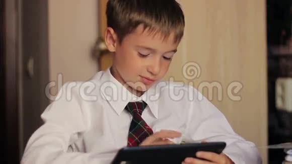 穿着白色衬衫和领带的男孩坐在他的书桌前视频的预览图