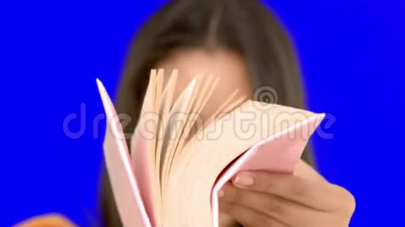 女人在蓝屏上翻着粉红色的书视频的预览图