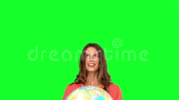 在绿色屏幕上抛掷地球仪的女人视频的预览图