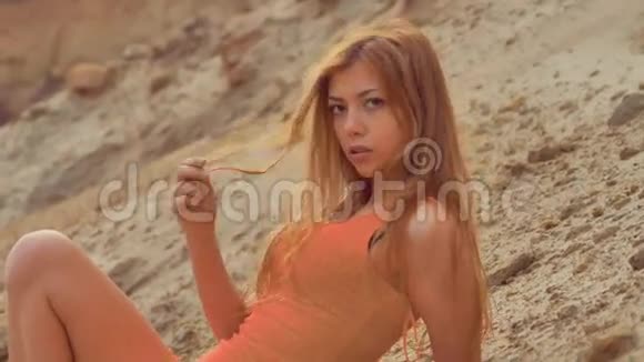 金发女孩躺在沙滩上看着摄像机视频的预览图