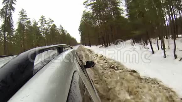 在森林的冬季道路上行驶时摄像机安装在汽车上它会变成雪视频的预览图