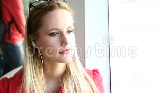 年轻漂亮的金发女人坐电车听音乐视频的预览图