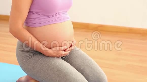 跪在蓝色运动垫上的孕妇视频的预览图