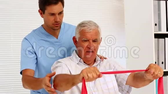 男性护士向老年患者展示如何使用阻力带视频的预览图