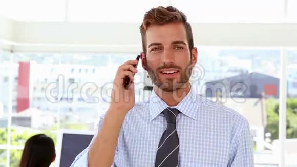 当同事在他身后工作时男人在打电话视频的预览图