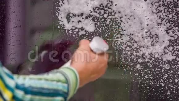 室内窗户上的人手喷洗泡沫视频的预览图