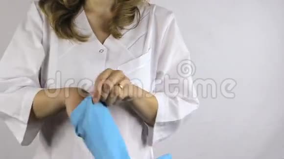 穿白色长袍的女人双手戴蓝色橡胶手套视频的预览图