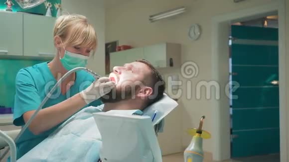 女性牙医检查男性患者的牙齿并寻找相机视频的预览图