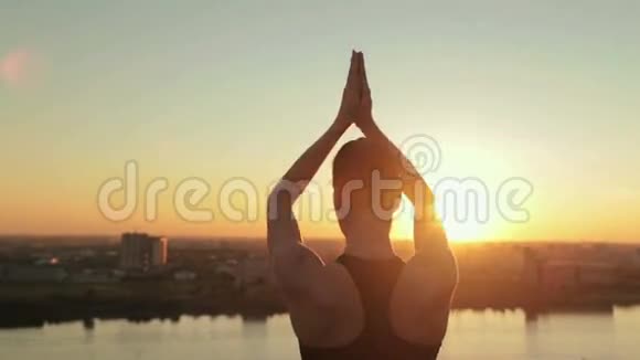 日落时分在公园里练习瑜伽的运动女人太阳敬礼视频的预览图