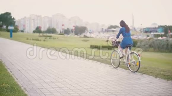 在城市里一个女孩骑着一辆自行车在篮子里放着鲜花和法国面包慢的稳定的镜头视频的预览图