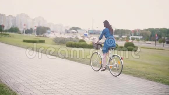 在城市里一个女孩骑着一辆自行车在篮子里放着鲜花和法国面包慢的稳定的镜头视频的预览图