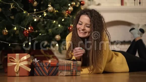 女人在圣诞树下打开新年礼物视频的预览图