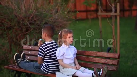男孩和女孩坐在长凳上绕着公园跑吹蒲公英视频的预览图