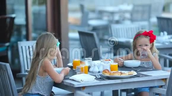 可爱的小女孩在户外咖啡馆吃早餐视频的预览图