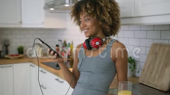 休闲女性在厨房里用电话放松视频的预览图