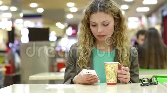 快乐的年轻女人在咖啡店喝咖啡或茶用手机视频的预览图