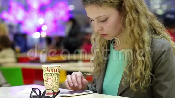快乐的年轻女人在咖啡店喝咖啡或茶用手机视频的预览图